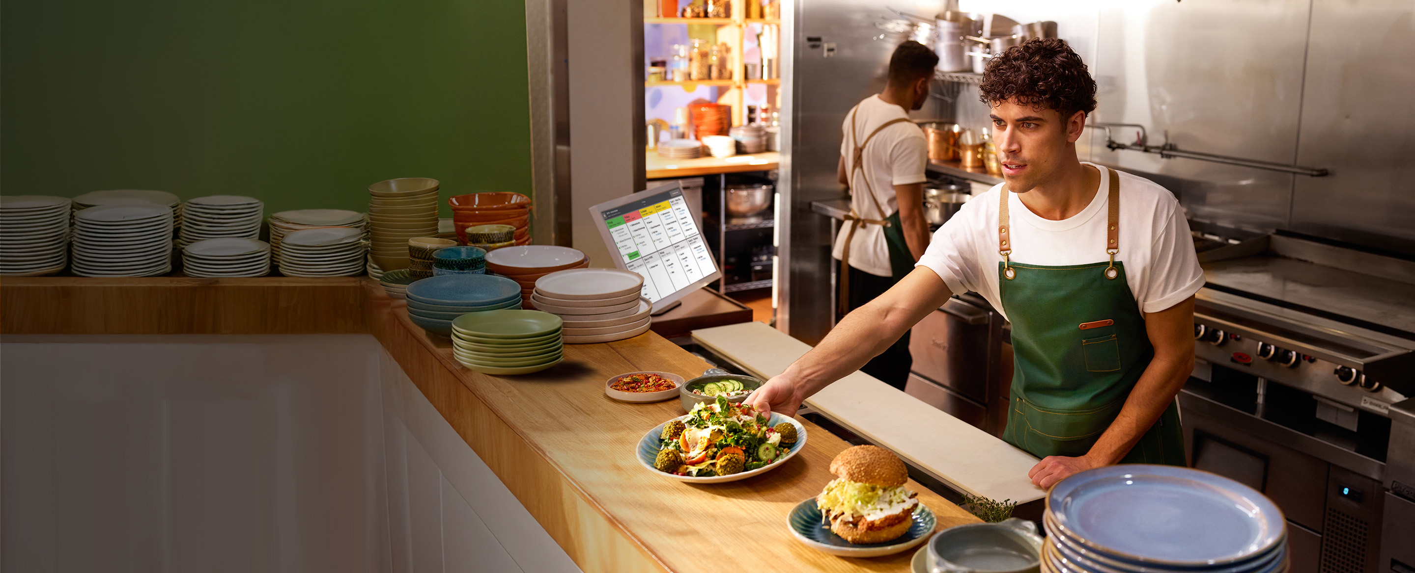 Chef plating a dish next to a kitchen display system